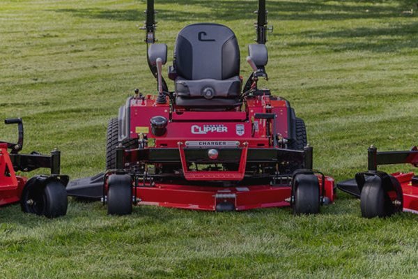 Three red zero-turn mowers parked side by side on a lawn
