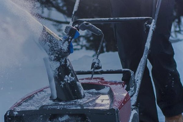 Single-stage snow blower clearing a snowy driveway